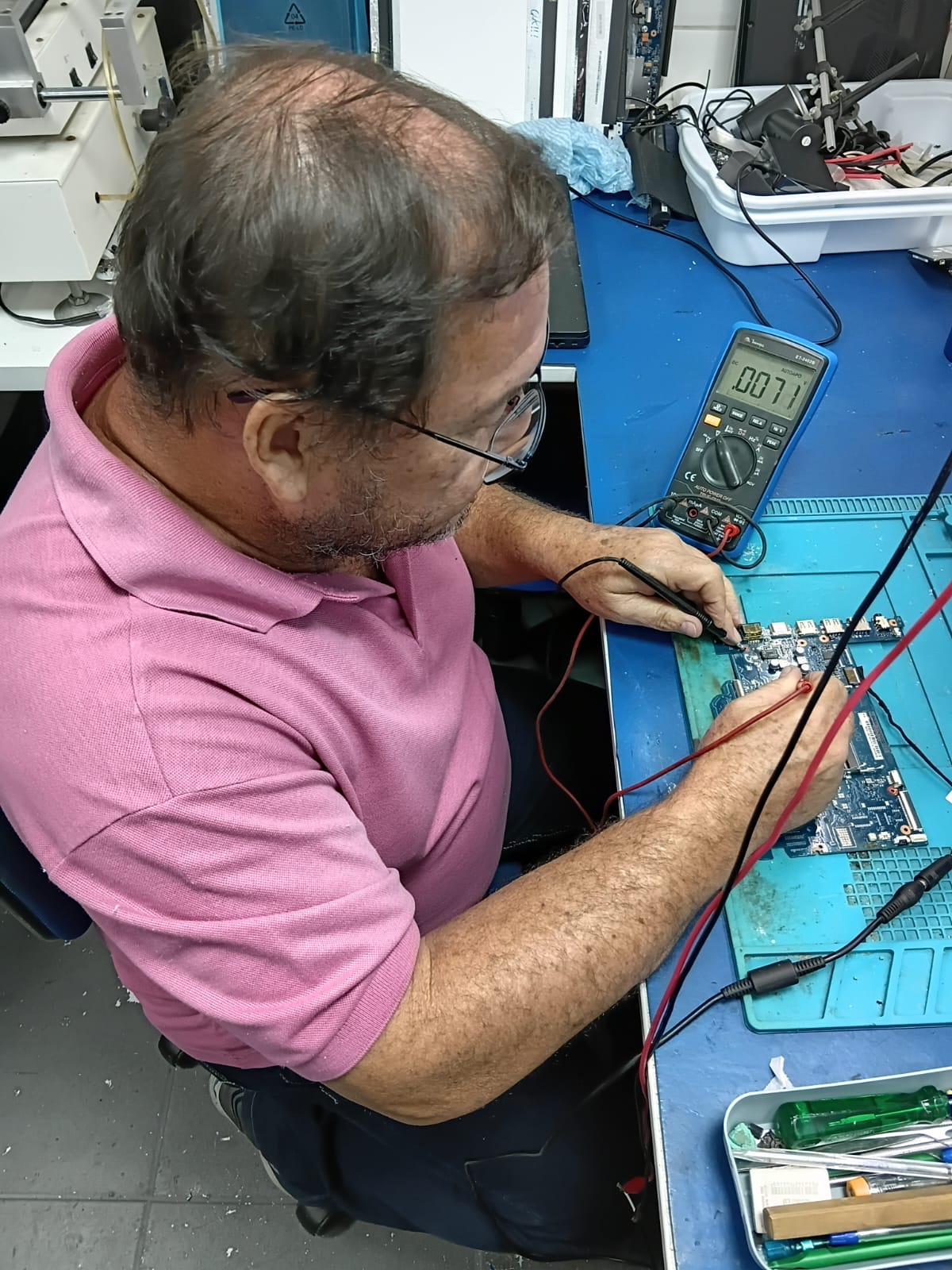 Técnico realizando reparo de placa de notebook em laboratório